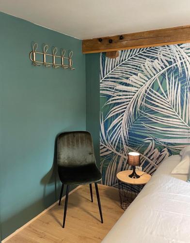 a bedroom with a bed and a black chair at Lilas, Dahlia, Palme Bleue in Saint-Aignan