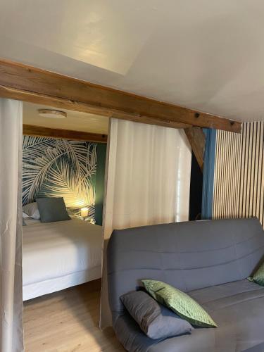 a bedroom with a bed and a couch in a room at Lilas, Dahlia, Palme Bleue in Saint-Aignan