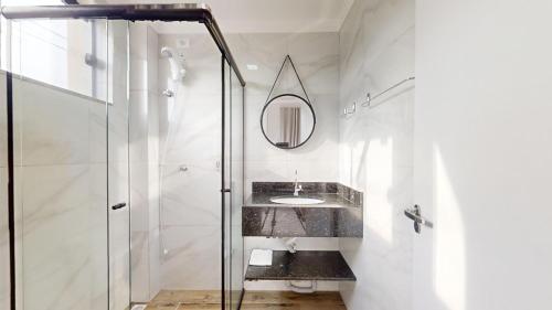 Un baño con ducha de cristal y lavabo. en Residencial Batista, en Bombinhas