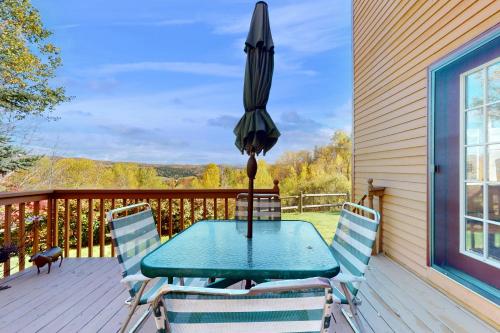 a table and chairs on a deck with an umbrella at Green Mountain Sunrise in Dover