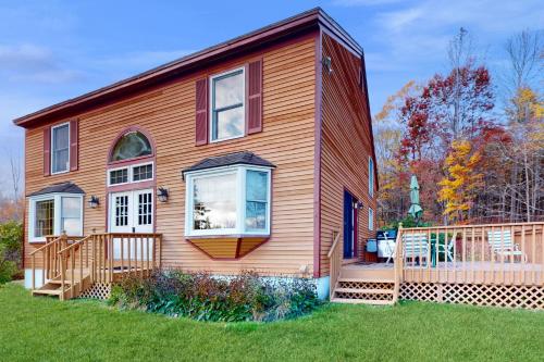 a large house with a deck on a lawn at Green Mountain Sunrise in Dover