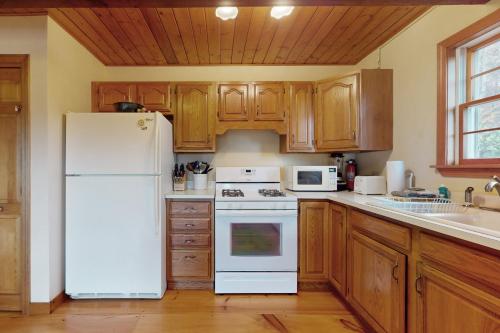a kitchen with a white refrigerator and wooden cabinets at Green Mountain Sunrise in Dover