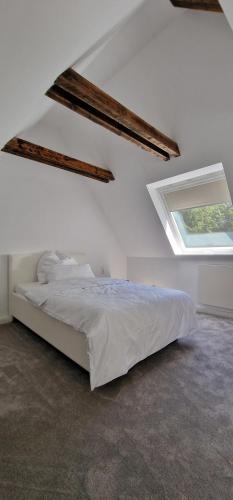 a bedroom with a bed in a white room with a window at Ruhiges Haus im Grünen mit Whirlpool & 3 Schlafzimmern nahe Messe Essen in Essen