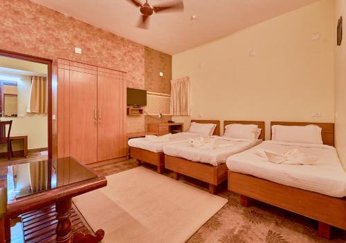 a hotel room with two beds and a television at Ushasree Wayanad Pool Resort by VOYE HOMES in Ambalavayal