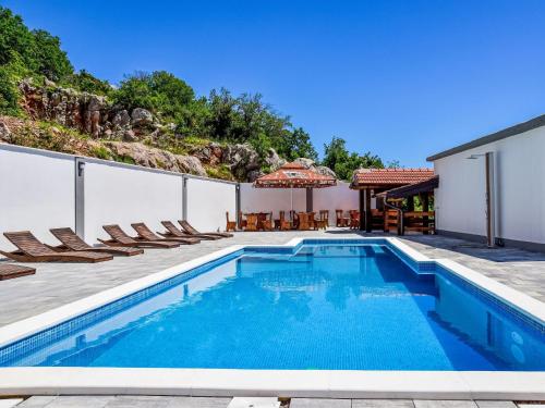 a swimming pool with chairs and a house at Apartment Delfin-11 by Interhome in Karlobag