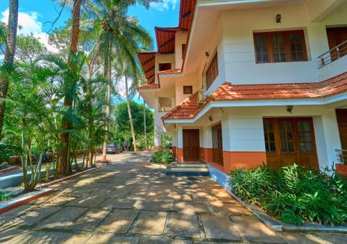 a house with palm trees on a street at Ushasree Wayanad Pool Resort by VOYE HOMES in Ambalavayal