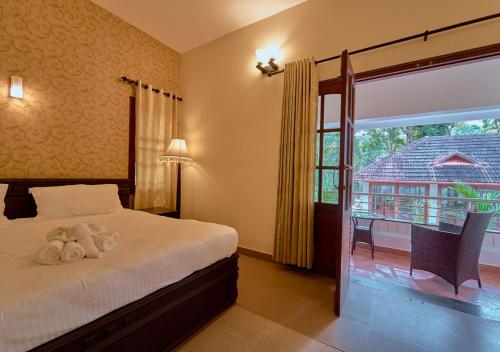 a bedroom with a bed and a window with a balcony at Ushasree Wayanad Pool Resort by VOYE HOMES in Ambalavayal
