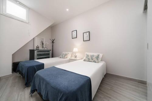 two beds in a white room with a window at Stylish apartment old town in Portimão