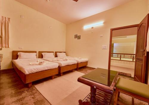 a room with two beds and a table in it at Ushasree Wayanad Pool Resort by VOYE HOMES in Ambalavayal