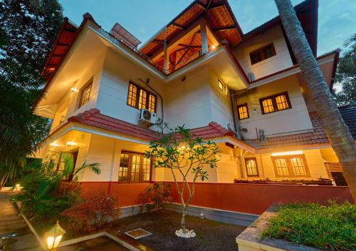 a large white house with a lot of windows at Ushasree Wayanad Pool Resort by VOYE HOMES in Ambalavayal