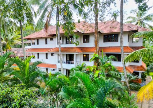 a building in the middle of a forest of palm trees at Ushasree Wayanad Pool Resort by VOYE HOMES in Ambalavayal
