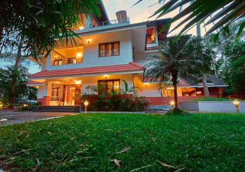 a large house with a lawn in front of it at Ushasree Wayanad Pool Resort by VOYE HOMES in Ambalavayal