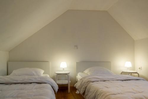 two beds in a white room with two lamps at Gite lilas in Le Pont-de-Montvert