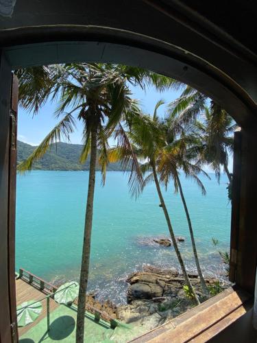 a view from a window of a beach with palm trees at Pousada Ponta da Ilha, Ilha Grande, Angra dos Reis in Angra dos Reis