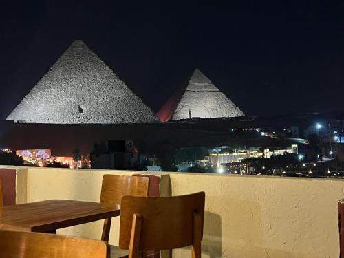 a table and chairs on a balcony with pyramids at Cheristo pyramids view inn in Cairo