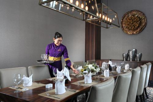 a woman is standing at a table in a restaurant at Swiss-Belinn Karawang in Karawang