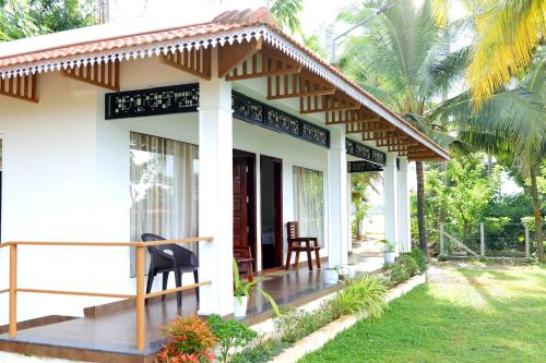 a small white house with a black chair in front of it at Riverview villa in Alleppey