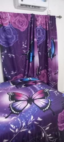 a purple bed with a butterfly design on it at Holiday rooms in St Thomas Jamaica in Clifton