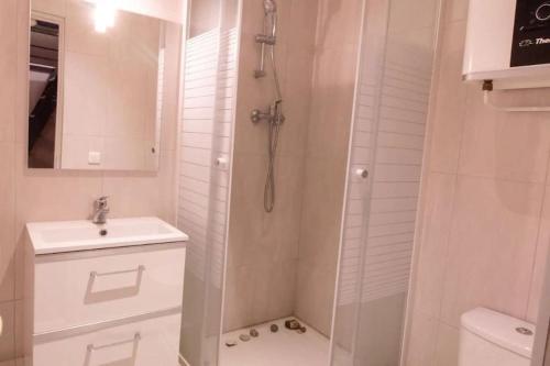 une salle de bain blanche avec une douche et un lavabo dans l'établissement Bel Appartement Parisien, TYPIQUE DU MARAIS, à Paris