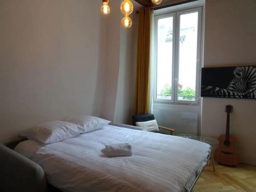 une chambre avec un lit blanc et une fenêtre dans l'établissement Bel Appartement Parisien, TYPIQUE DU MARAIS, à Paris