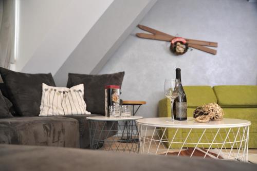 a living room with a couch and two tables with wine glasses at Apartman Family Konaci in Kopaonik