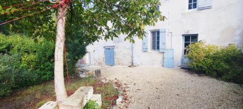 un bâtiment blanc avec des portes bleues et un arbre dans l'établissement Gîte 2 personnes, à Courcoury