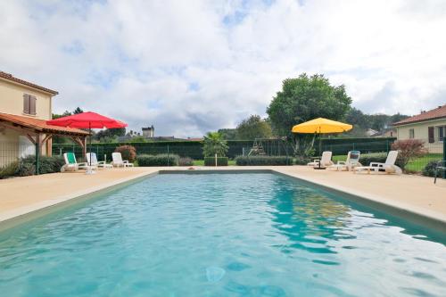une piscine avec chaises et parasols dans une cour dans l'établissement Le Baradis avec Piscine et Clim, à Savignac-les-Églises