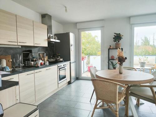 une cuisine avec une table en bois et une table et des chaises dans l'établissement Spacieux appartement lumineux, à Colmar