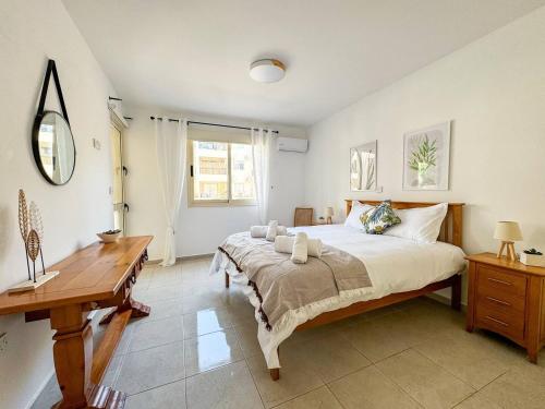 a bedroom with a large bed and a wooden desk at Royal-seacrest Oasis, Pool-side in Paphos City