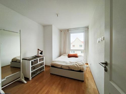 une chambre avec un lit, une commode et une fenêtre dans l'établissement Spacieux appartement lumineux, à Colmar