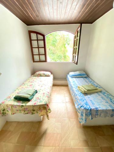 two beds in a room with a window at Pousada Ponta da Ilha, Ilha Grande, Angra dos Reis in Angra dos Reis
