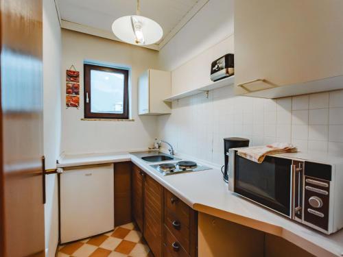 een kleine keuken met een spoelbak en een magnetron bij Apartment Landhaus St- Georg-3 by Interhome in Bad Gastein