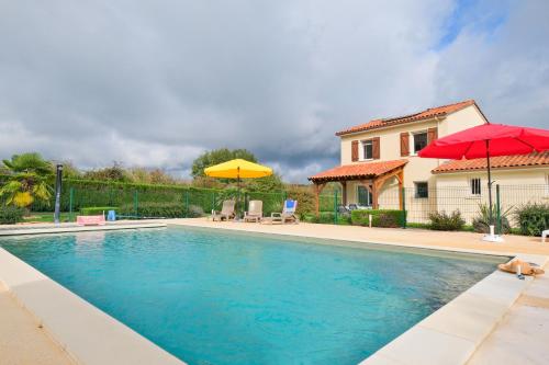 une piscine avec deux parasols et une maison dans l'établissement Duo de Maisons avec Piscine et Clim, à Savignac-les-Églises