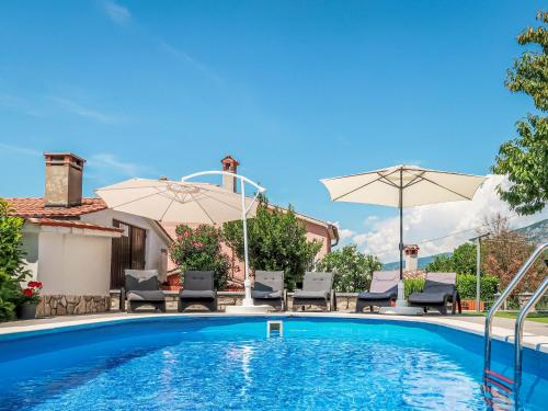 a swimming pool with two umbrellas and chairs at Holiday Home Villa Desanka by Interhome in Kršan