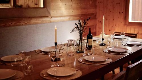 - une table en bois avec des assiettes, des verres et une bouteille de vin dans l'établissement Chalet Narnia, à Morzine