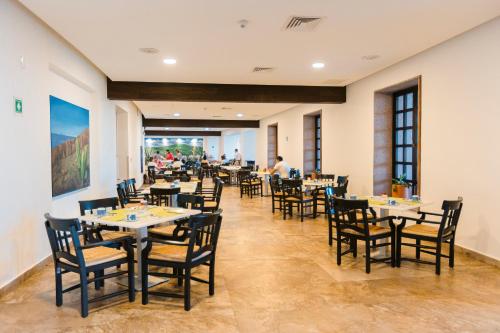 a restaurant with tables and chairs and a man in the background at Azul Ixtapa Grand All Inclusive Suites - Spa & Convention Center in Ixtapa