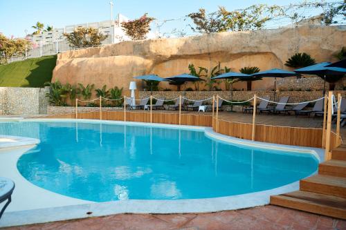 a large swimming pool with chairs and umbrellas at Villa Vittoria Hotel in Alcamo