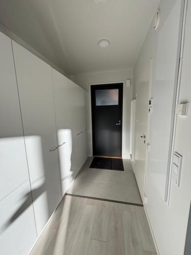 a hallway with white walls and a black door at Vesirattaantie Apartment in Espoo