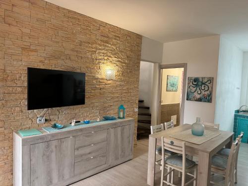 a living room with a television on a brick wall at Appartamento La Pelosa in Stintino