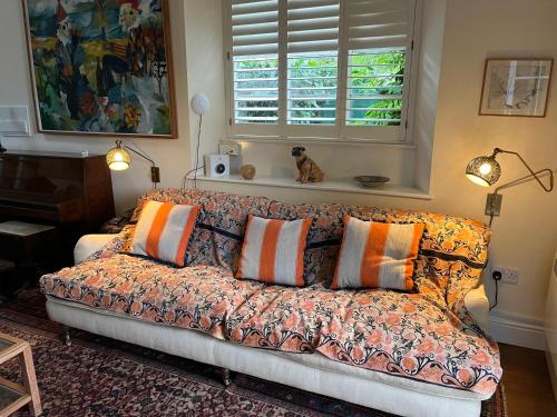 a couch with pillows in a living room with a window at Charming Old Schoolroom in Daventry