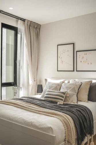 a white bedroom with a large bed with pillows at Title Halo Memories Naiyang Pool Gym Sauna in Nai Yang Beach