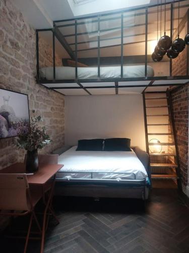 une chambre avec un lit, un bureau et un lit superposé dans l'établissement Le Petit Atelier Des Lumières, VÉRANDA AGRÉABLE, à Paris