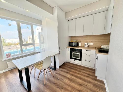 a kitchen with white cabinets and a table with chairs at Уютные апартаменты в новострое на Ботанике in Chişinău