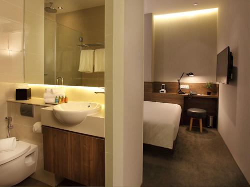 uma casa de banho com um lavatório branco e um WC. em Arcadia Hotel em Singapura