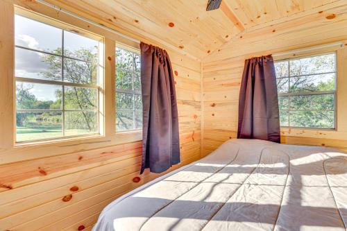 una cama en una cabaña de troncos con ventanas en Riverfront Cabin Near Yellowstone Lake State Park, en Blanchardville