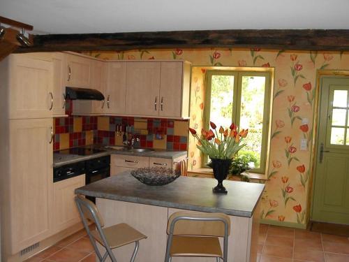 une cuisine avec un vase de fleurs sur un comptoir dans l'établissement La beuquette, à Jandun