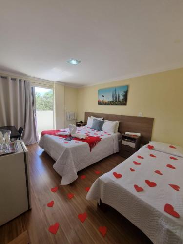 a bedroom with two beds with hearts on the floor at Pousada Coqueiral in Aracruz