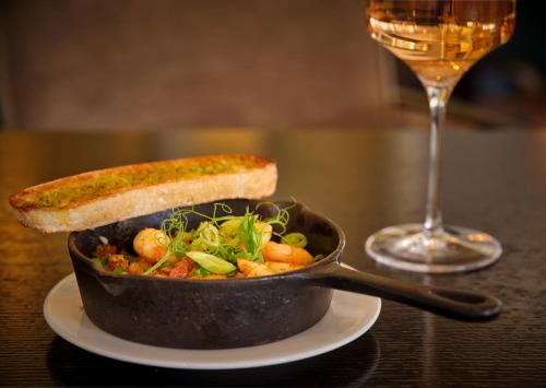 a pan of food with a piece of bread and a glass of wine at The College Green Dublin Hotel, Autograph Collection in Dublin