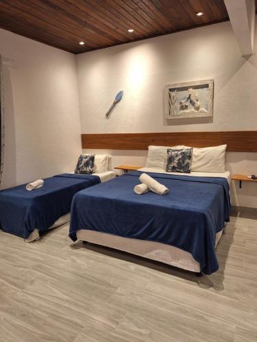 two beds in a room with blue sheets and a wall at Pousada Schueng in Trindade