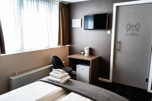a hotel room with a bed and a desk and a television at Hotel Du Commerce in Oostburg